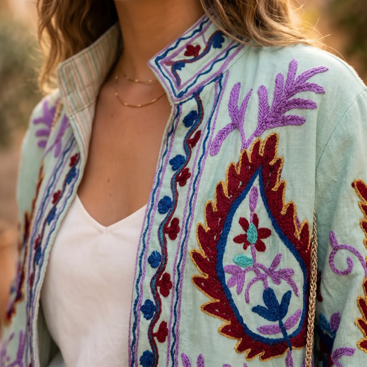 Primer plano de chaqueta corta en tono verde agua con bordados de paisley en granate, lila y azul Modamiomio